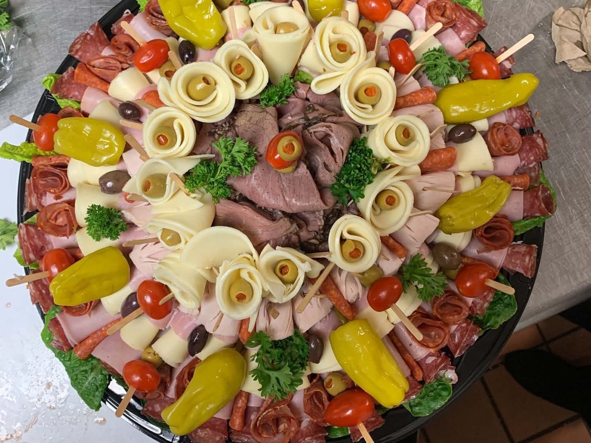 A deli and cheese catering platter with roast beef, cheese roses, and pepperoncini
